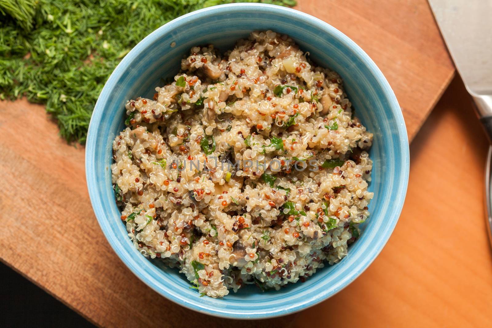 Bowl with Cereal Mix of Red and Whole Grain Quinoa on a wooden surface with dill