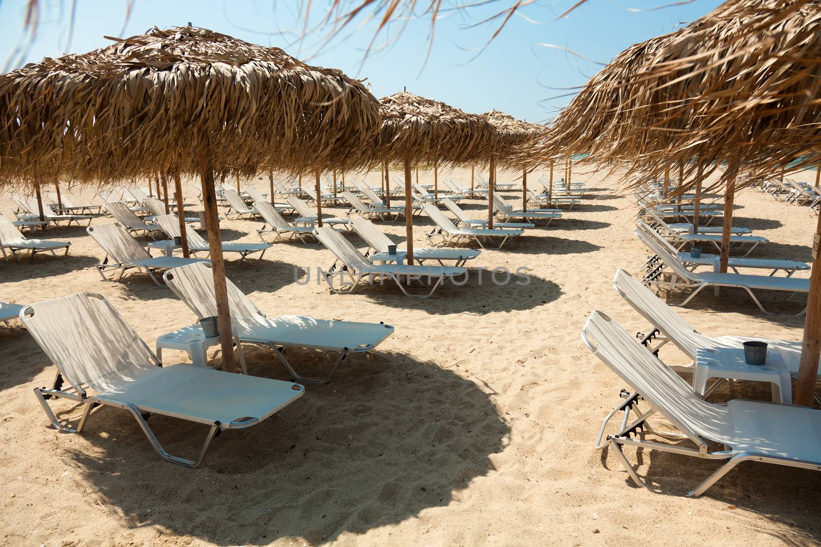 Beautiful beach with deck chairs and umbrellas on the sandy beach in Nea Irakleia (Halkidiki). Thessaloniki - Greece