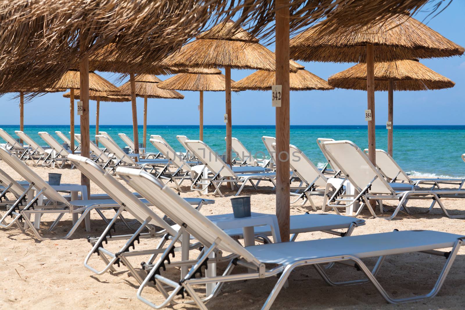 Beautiful beach with deck chairs and umbrellas on the sandy beach in Nea Irakleia (Halkidiki). Thessaloniki - Greece