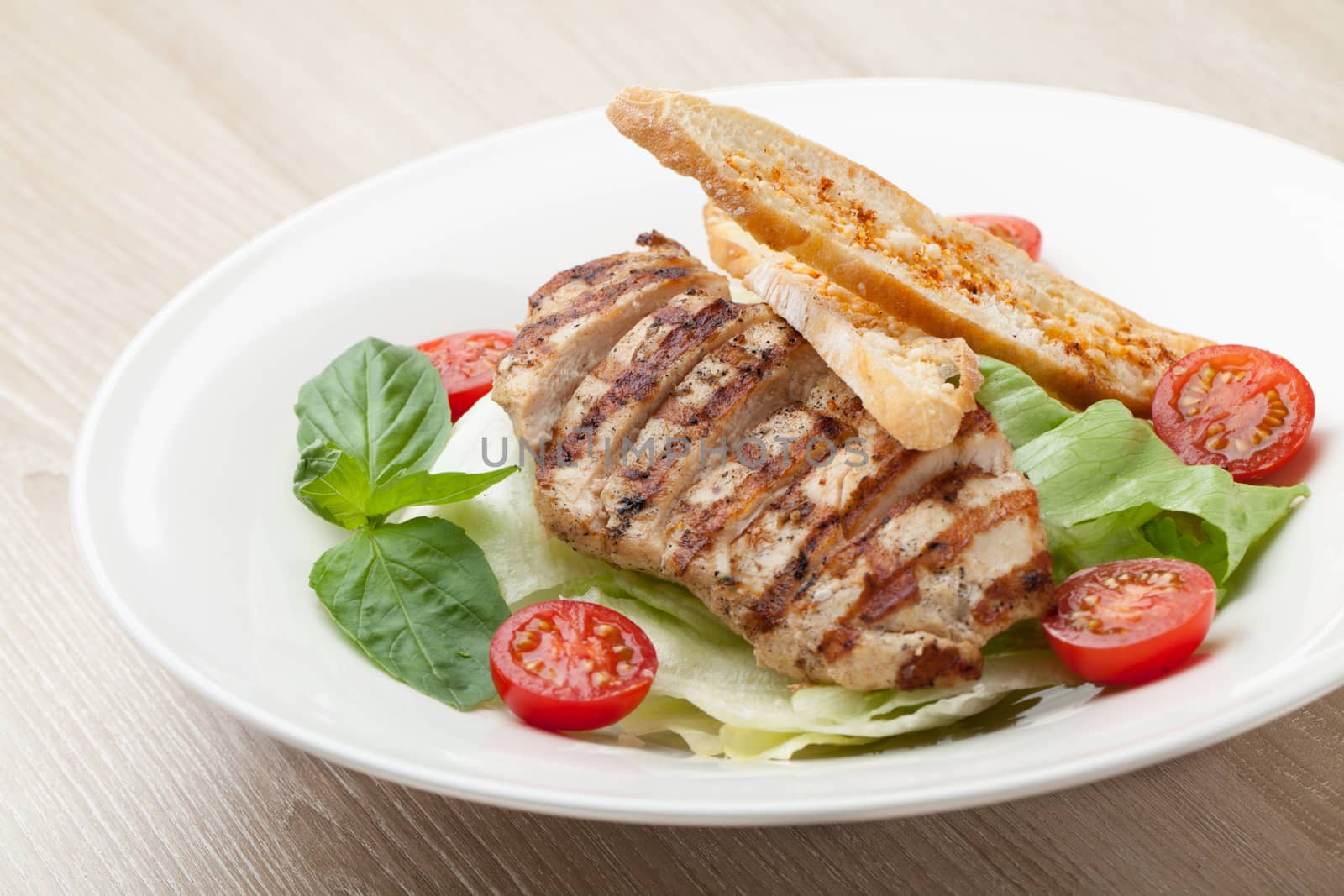 Gourmet delicious caesar salad with grilled beef meat fillet, romaine lettuce, cherry tomatoes,  cheese croutons and basil served in white plate