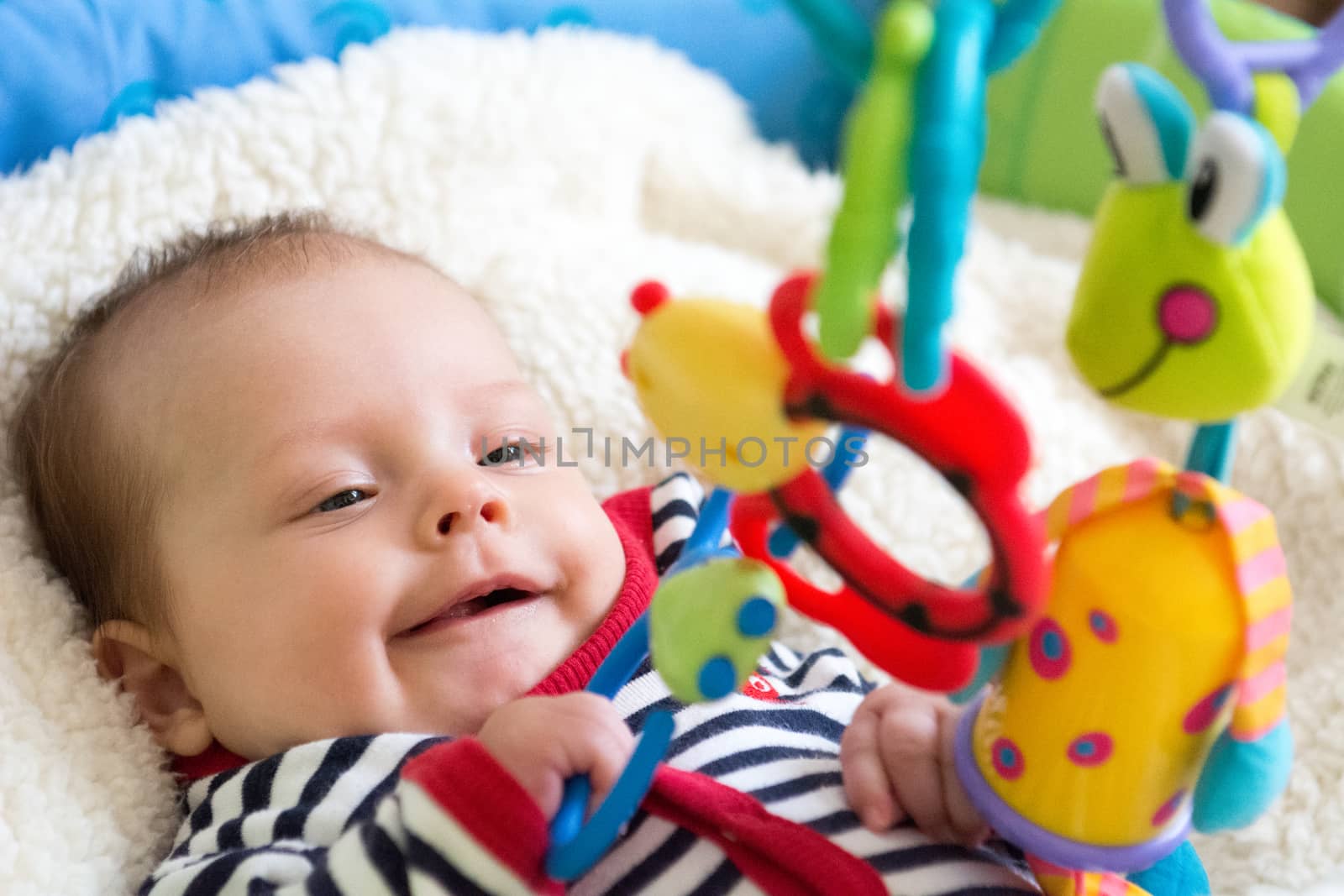 Happy baby girl grabbing a hanging down toy