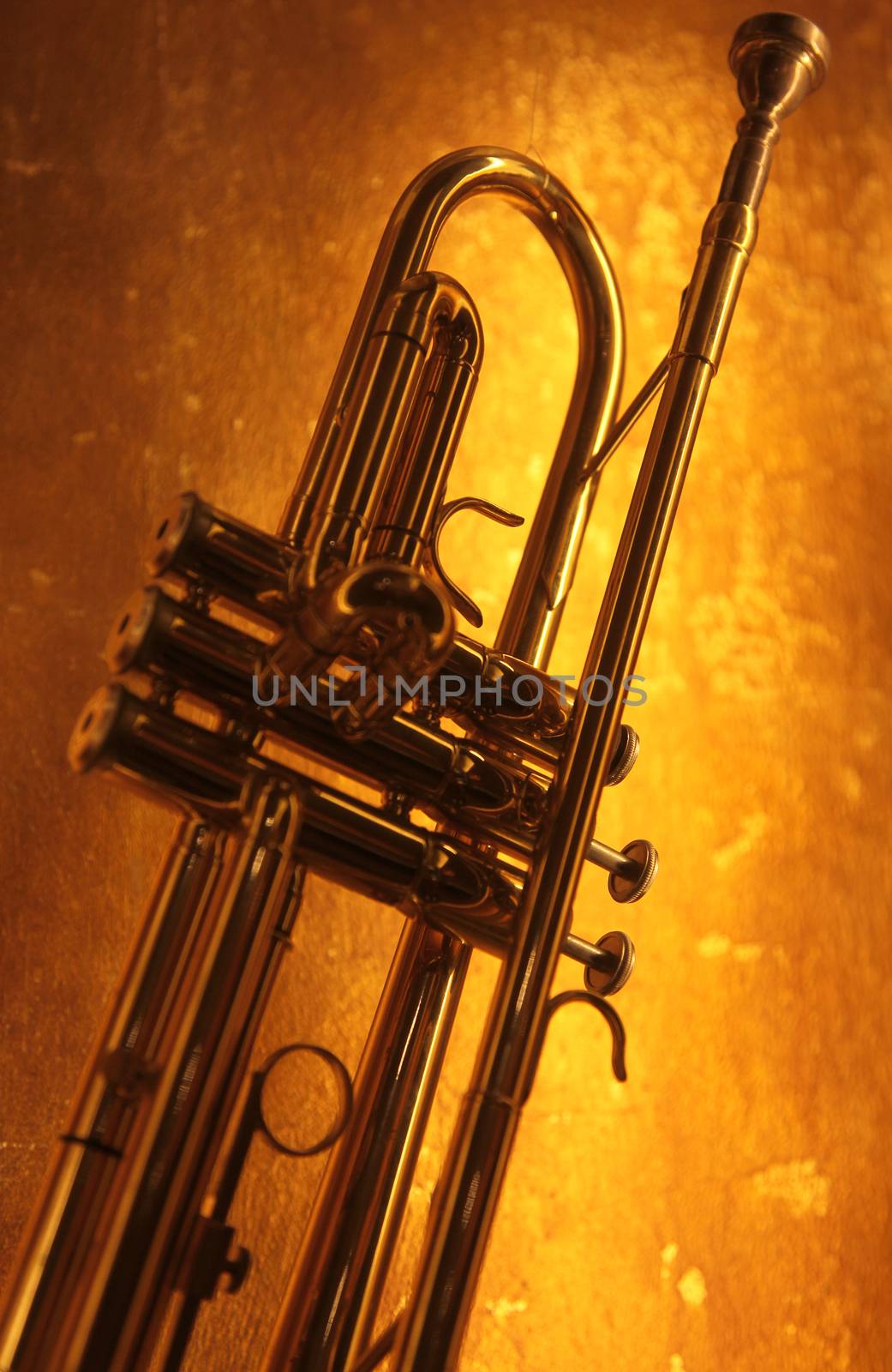 Brass trumpet horn on a golden background. Soft light photograph.