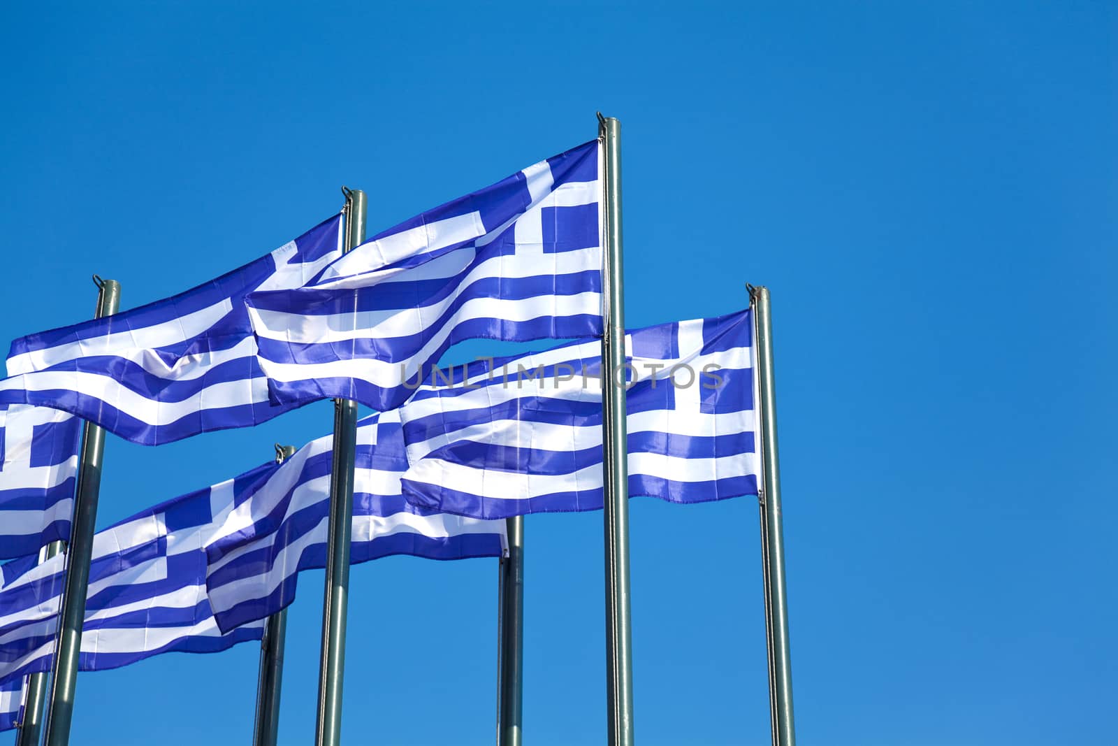 National Greek flags waving in wind against clear blue sky