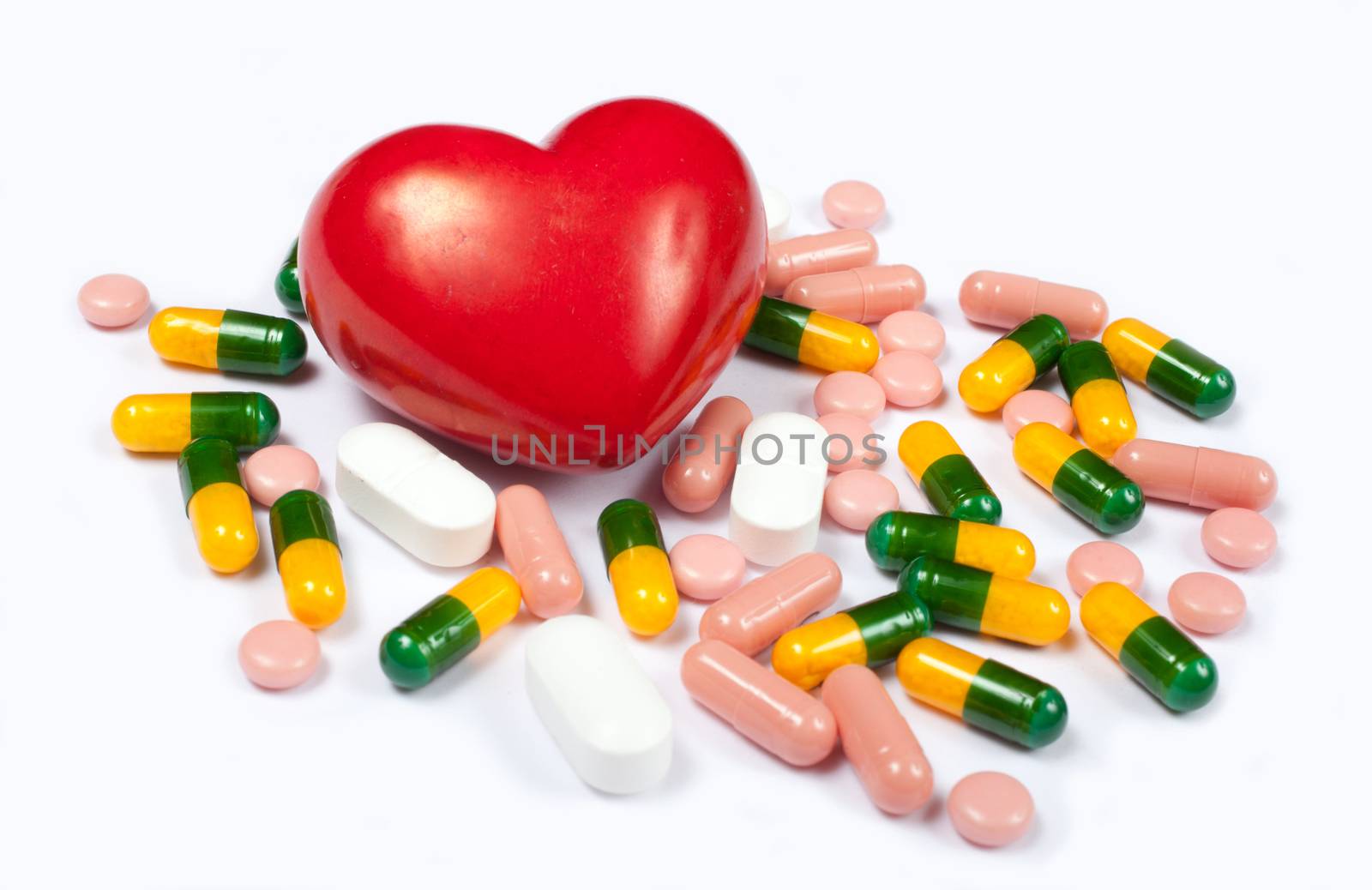 Red heart and pills on white background