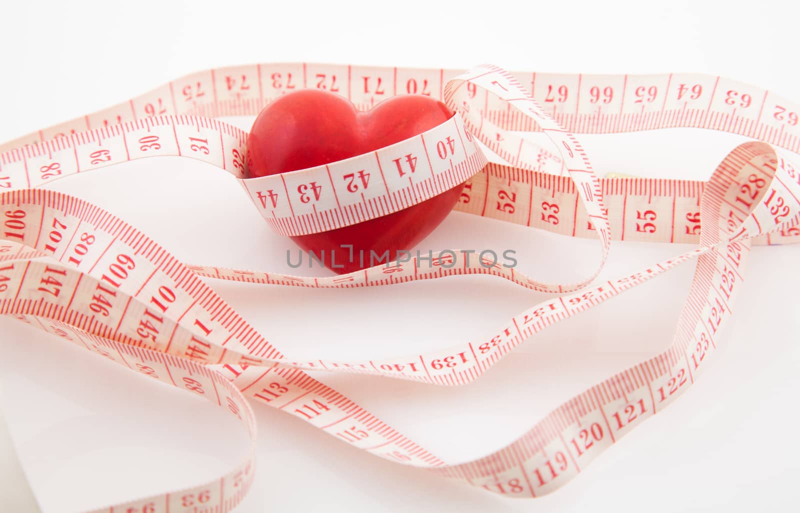 Red heart surrounded by a tape measure on white background