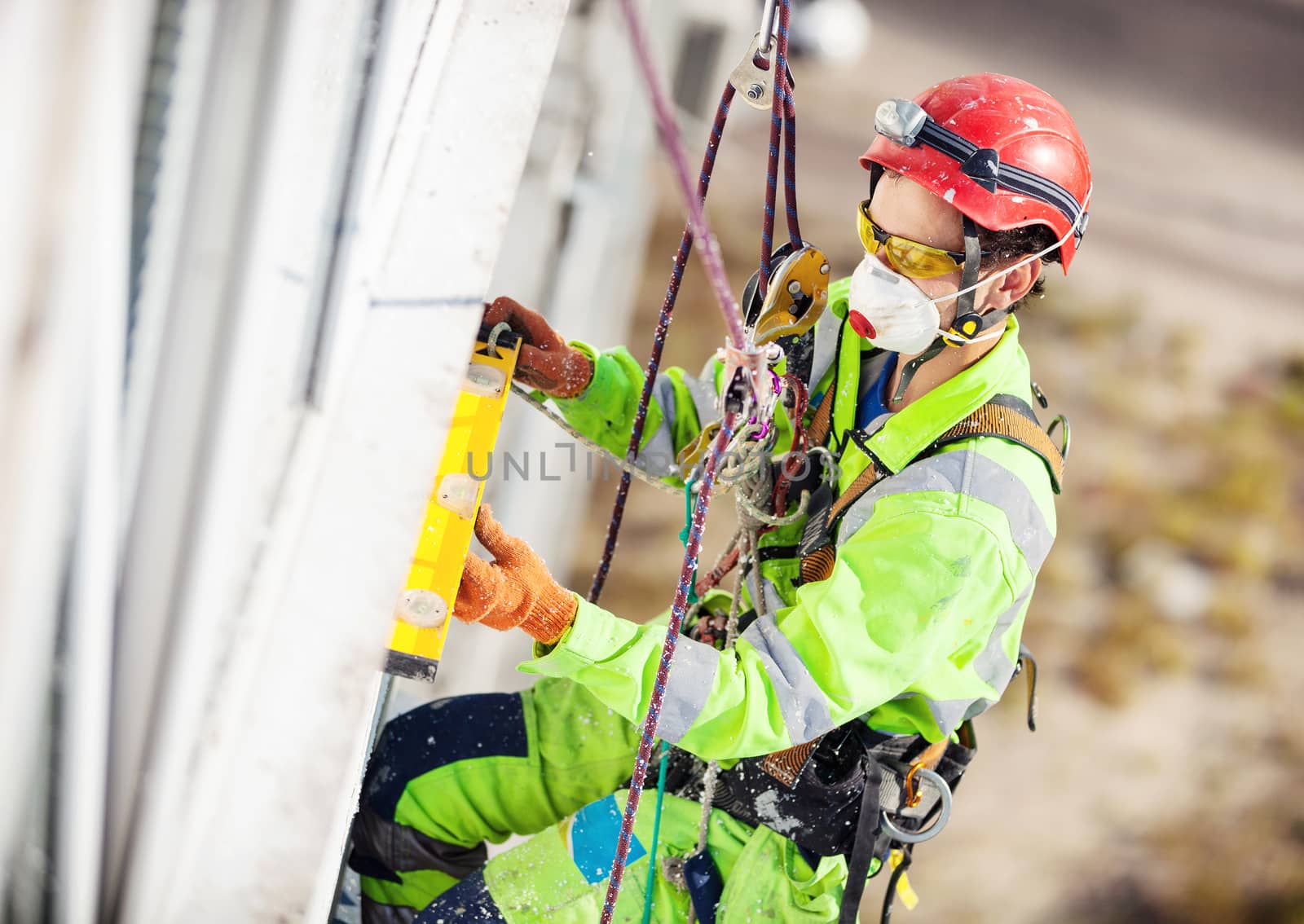 Industrial climber measuring with level tube during winterization works