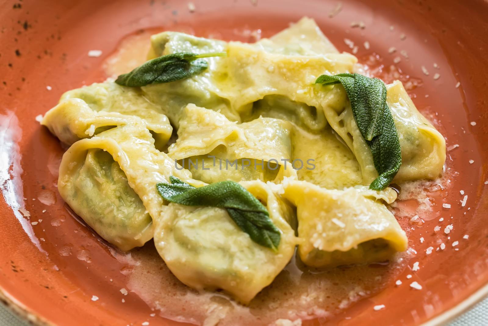 Ravioli pasta from green dough with mushroom stuffing, oil, parsley, vegetarian dish. selective focus