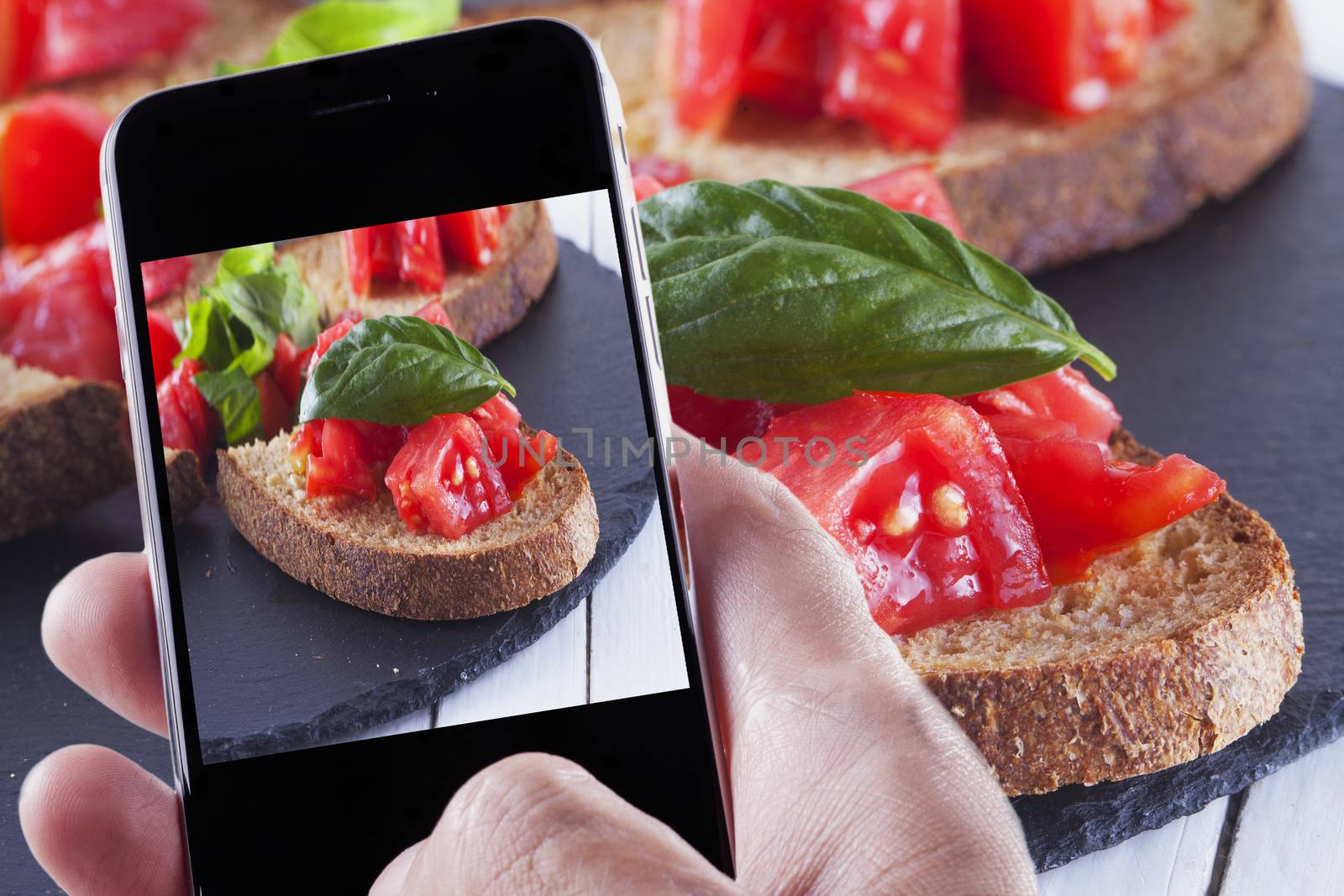 Male hand with smartphone taking a photo of food