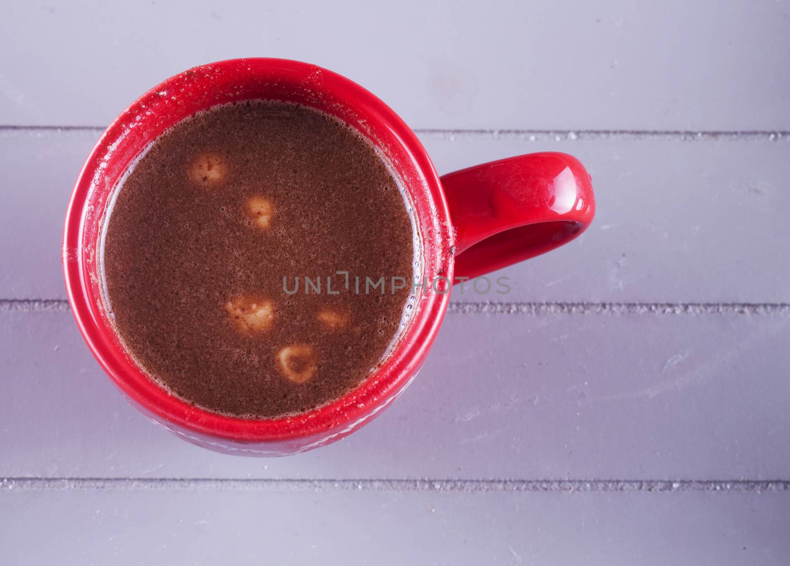 Chocolate and hazelnuts in red cup, over wooden background
