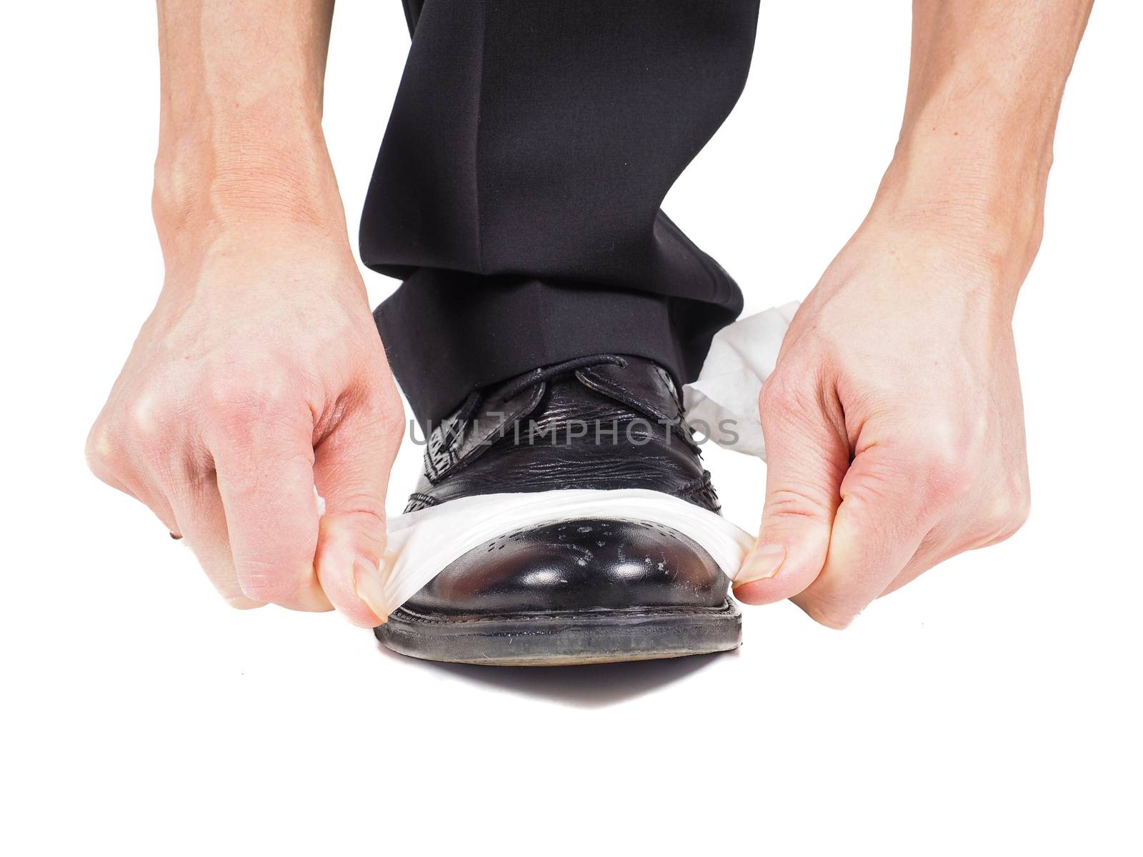 Closeup of male hands shining black leather shoes with a sheet of white tissue towards white background