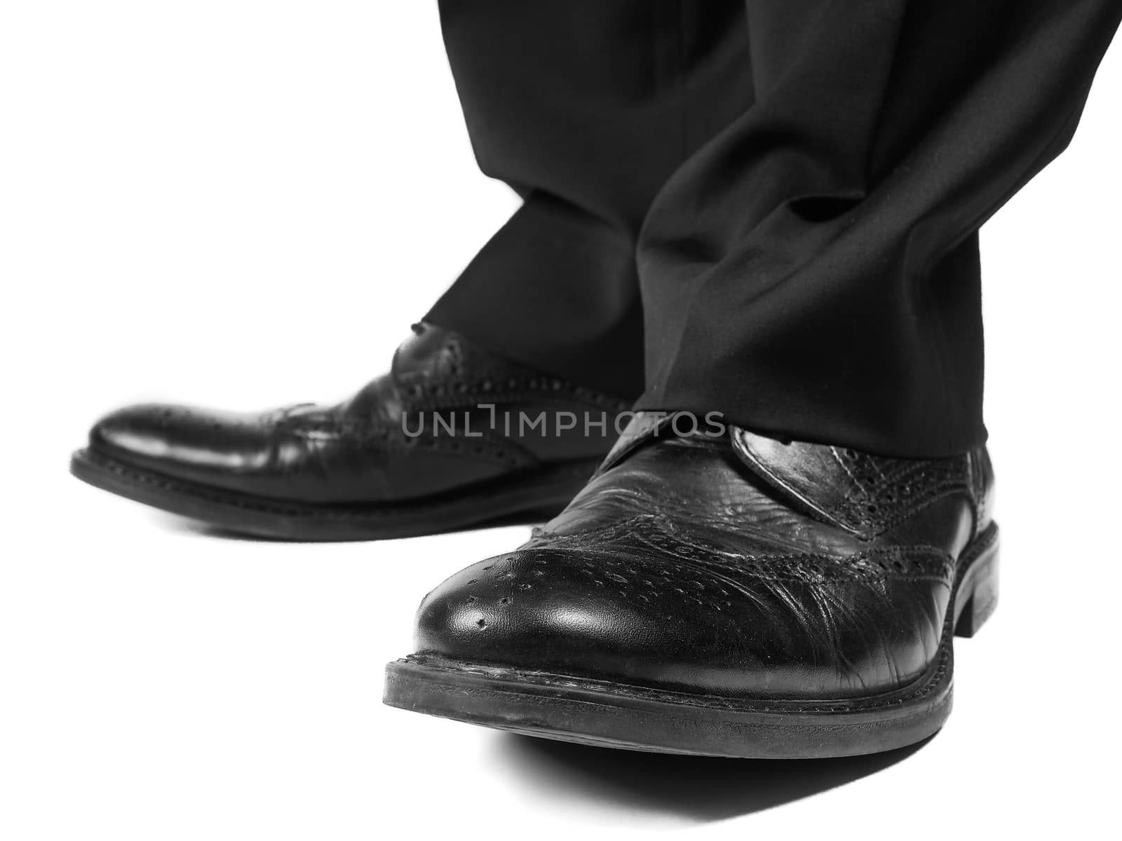 Masculine suit wearing shiny black leather shoes towards white