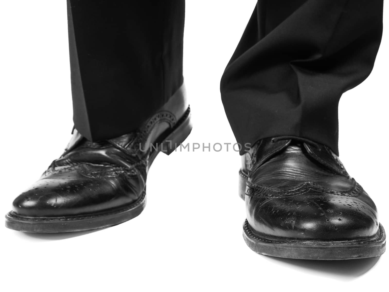 Masculine suit wearing shiny black leather shoes approaching towards white