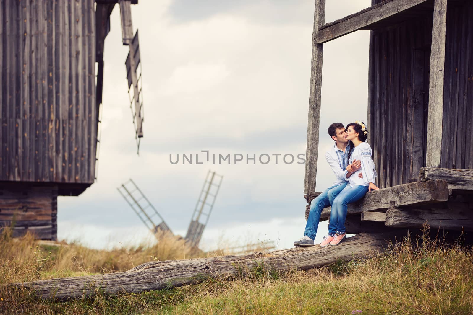Young couple kissing on steps of old windmill by photobac