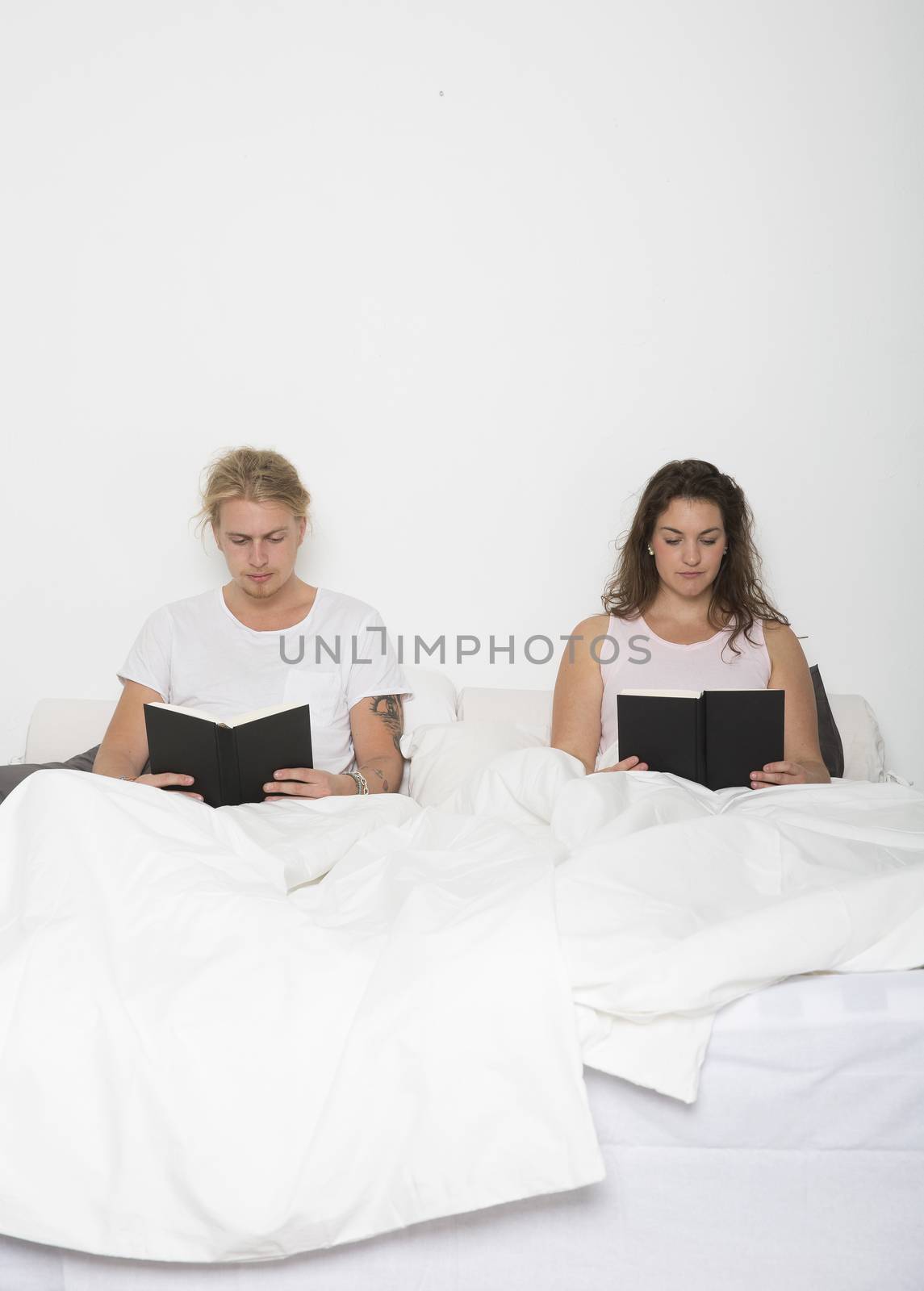Hetereosexuel couple reading books in bed