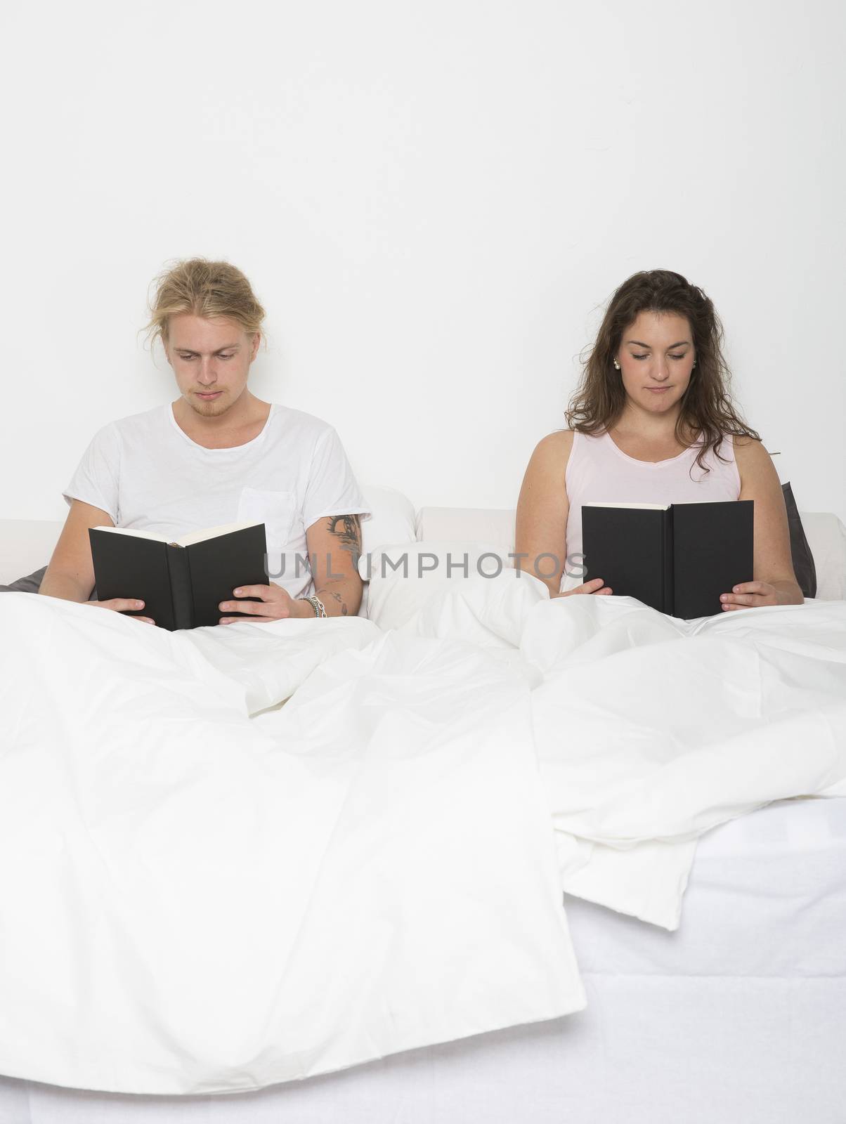 Hetereosexuel couple reading books in bed