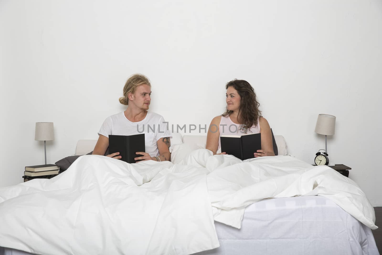 Hetereosexuel couple reading books in bed