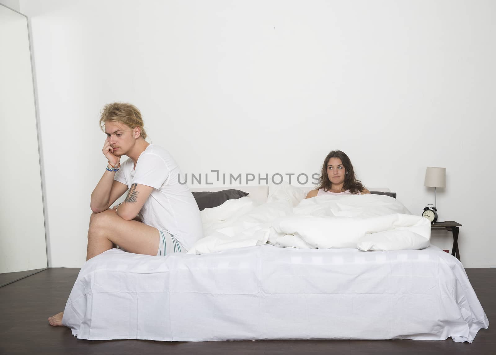 Sad man and his wife in bed