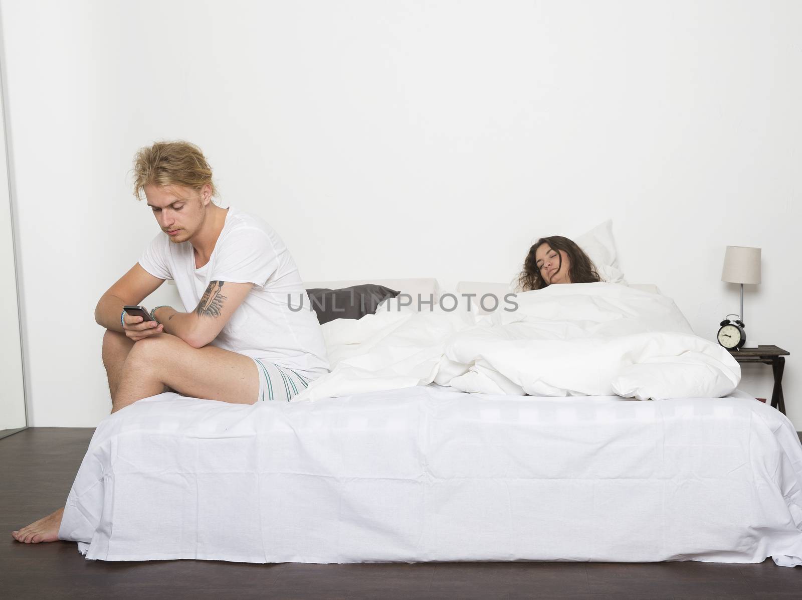 Man with his telephone while the wife sleeps