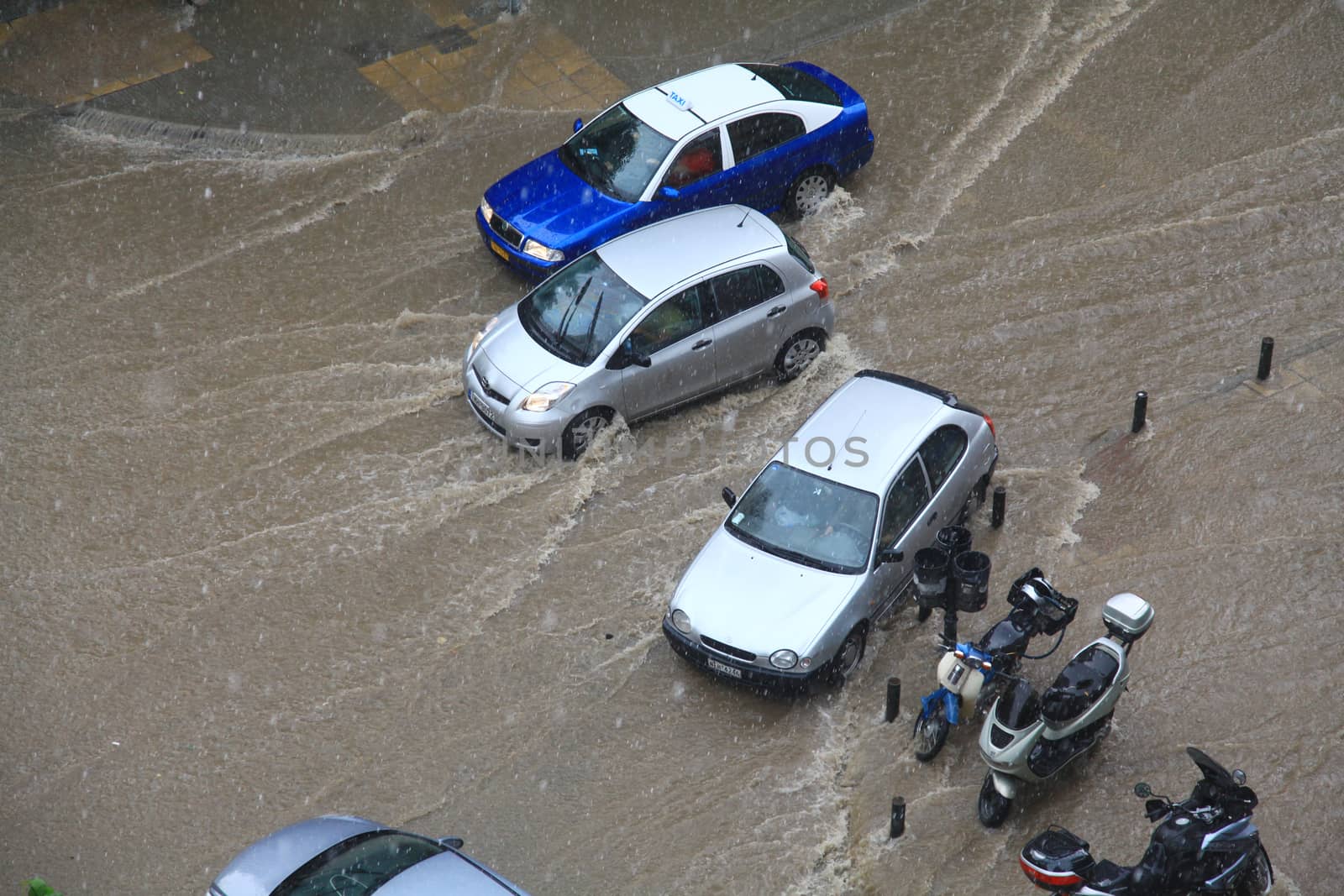 People try to cross a flooded road by Portokalis