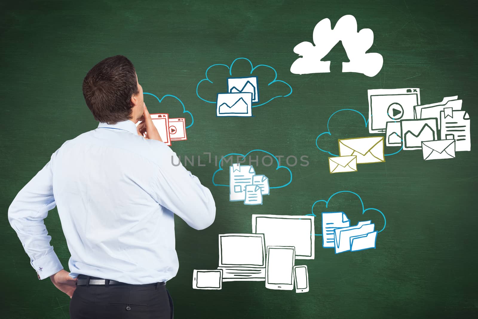 Thinking businessman touching his chin against green chalkboard with technology doodles