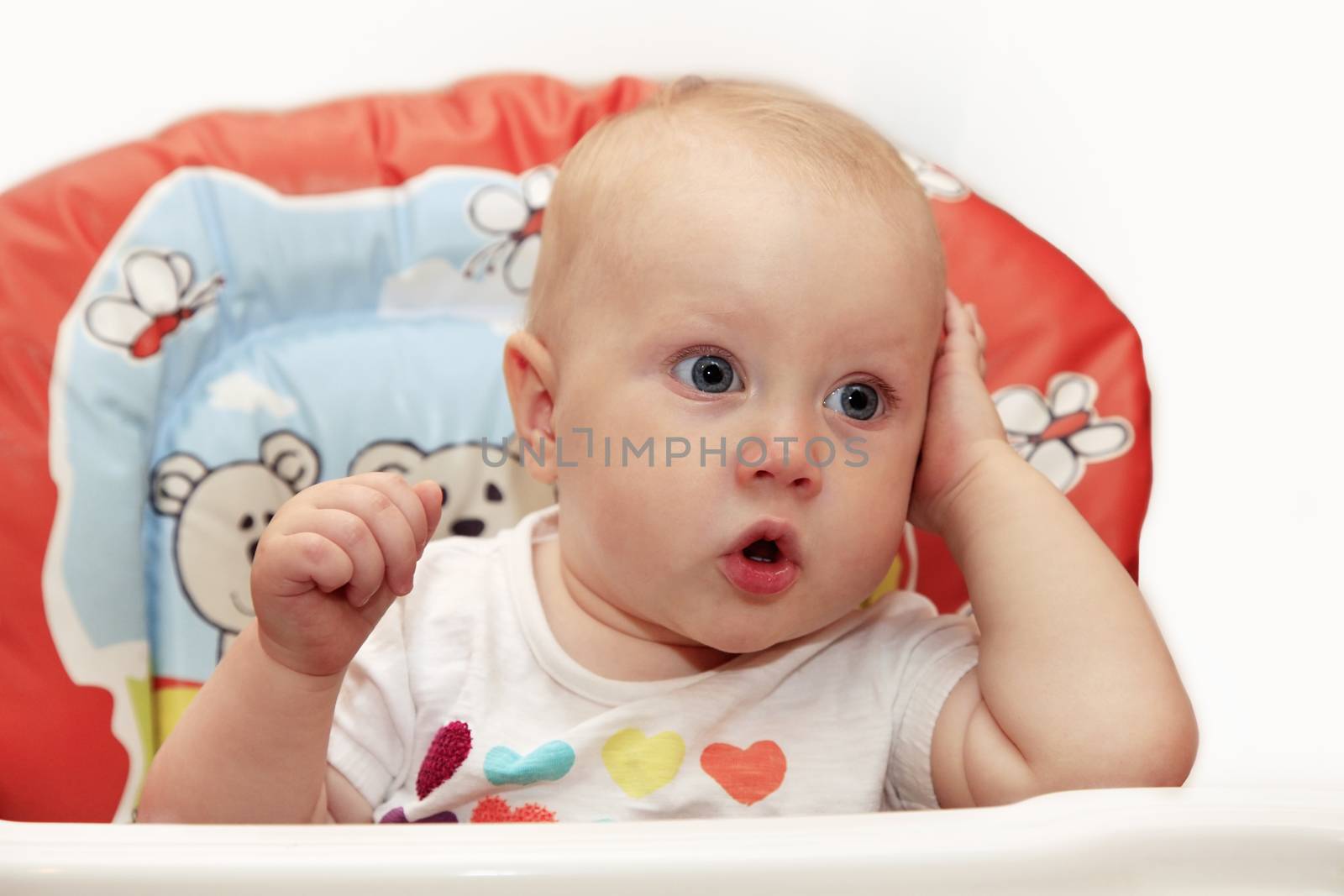 Surprised little girl sitting in baby chair