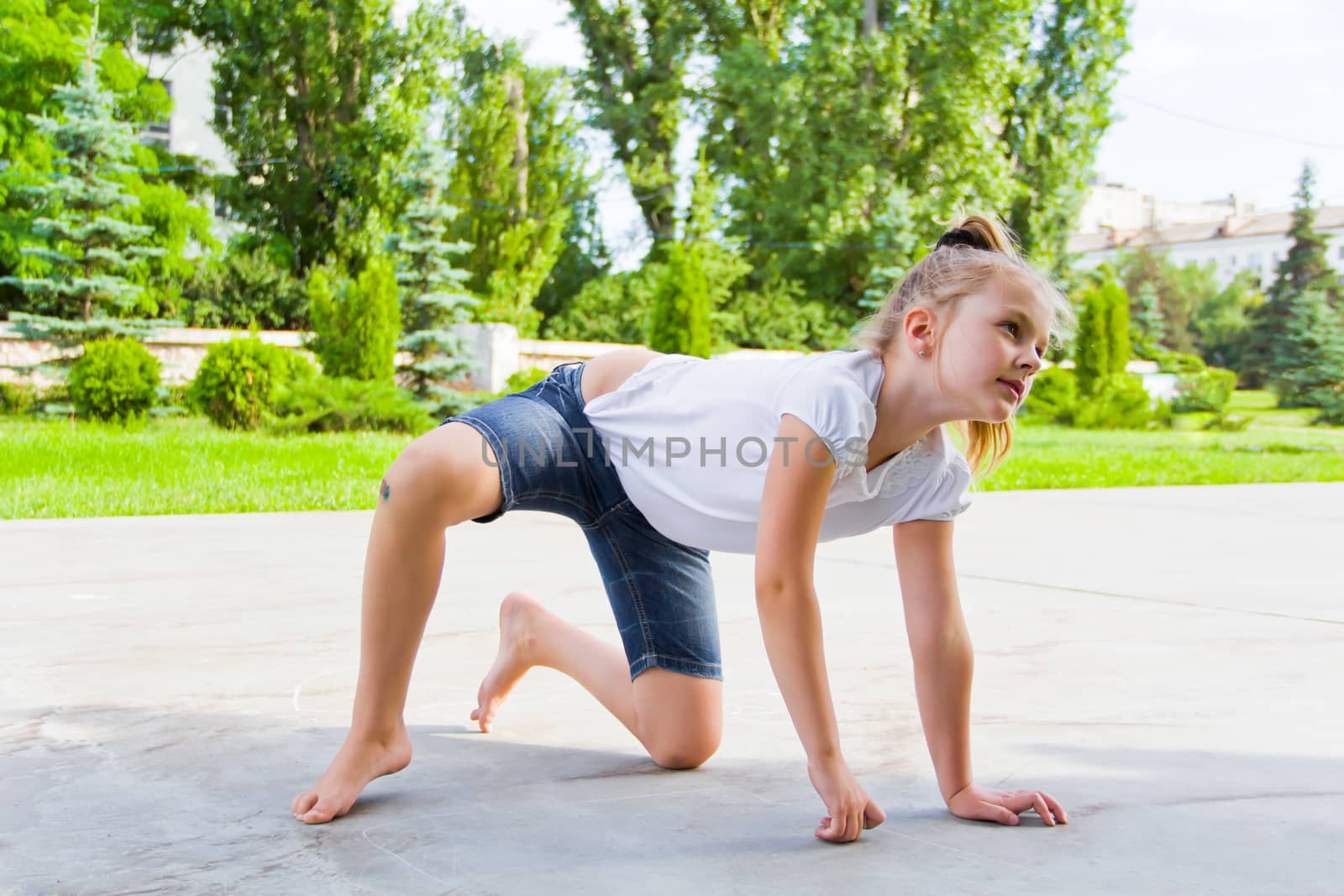 Cute girl draws chalk on asphalt in summer