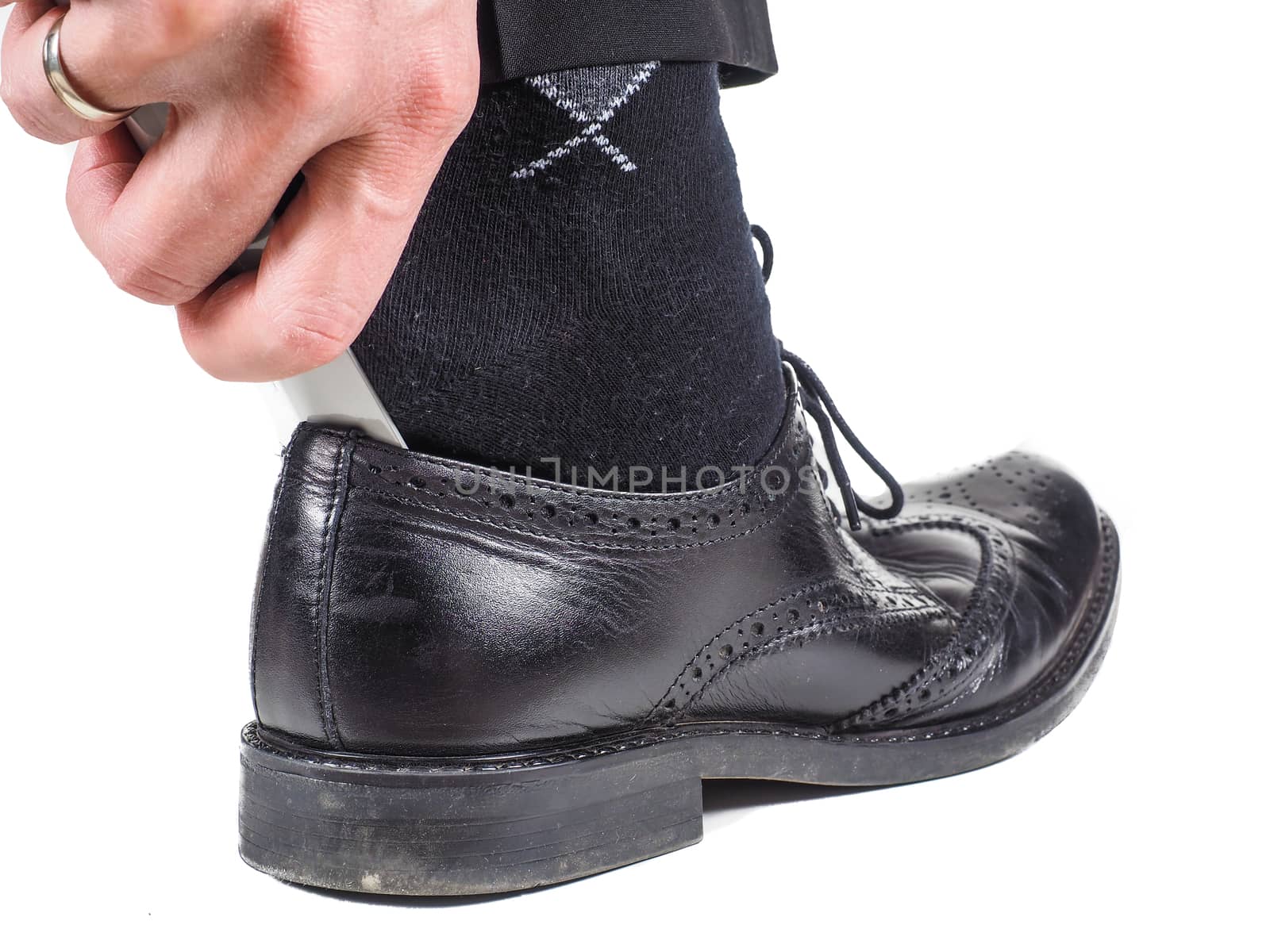 Male hand entering foot into black leather shoe by Arvebettum