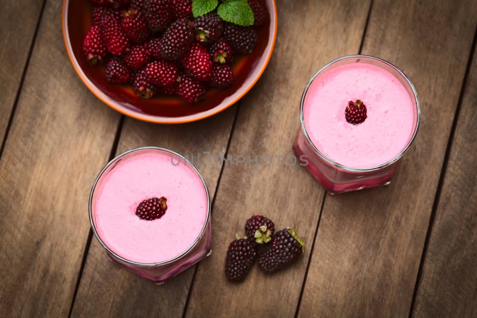 Freshly prepared blackberry milkshake in two glasses (Selective Focus, Focus on the top of the lower milkshake)