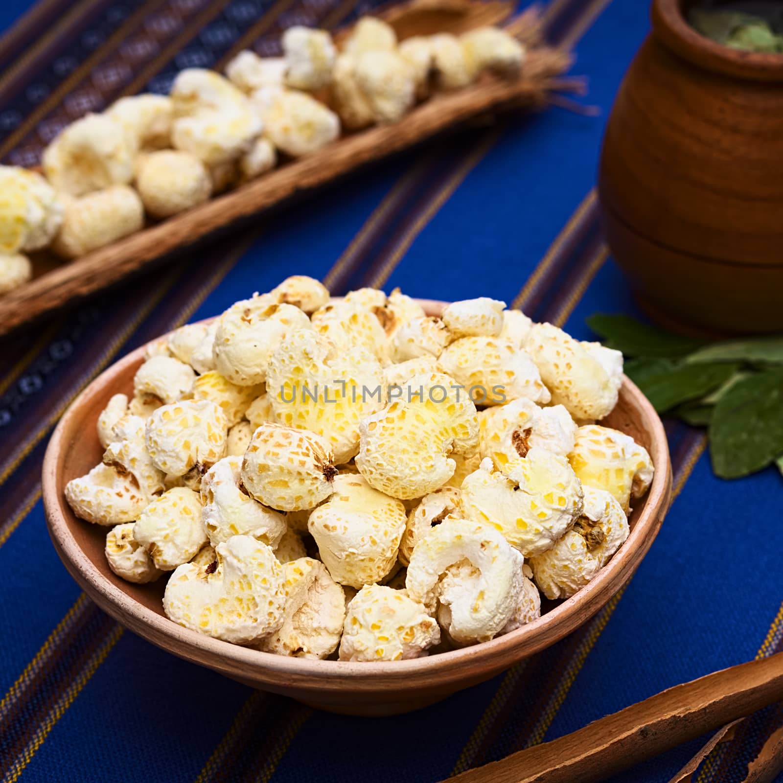Sweetened popped white corn called Pasancalla eaten as snack in Bolivia served in a clay bowl with coca tea in the back, photographed with natural light (Selective Focus, Focus in the middle of the snack) 
   