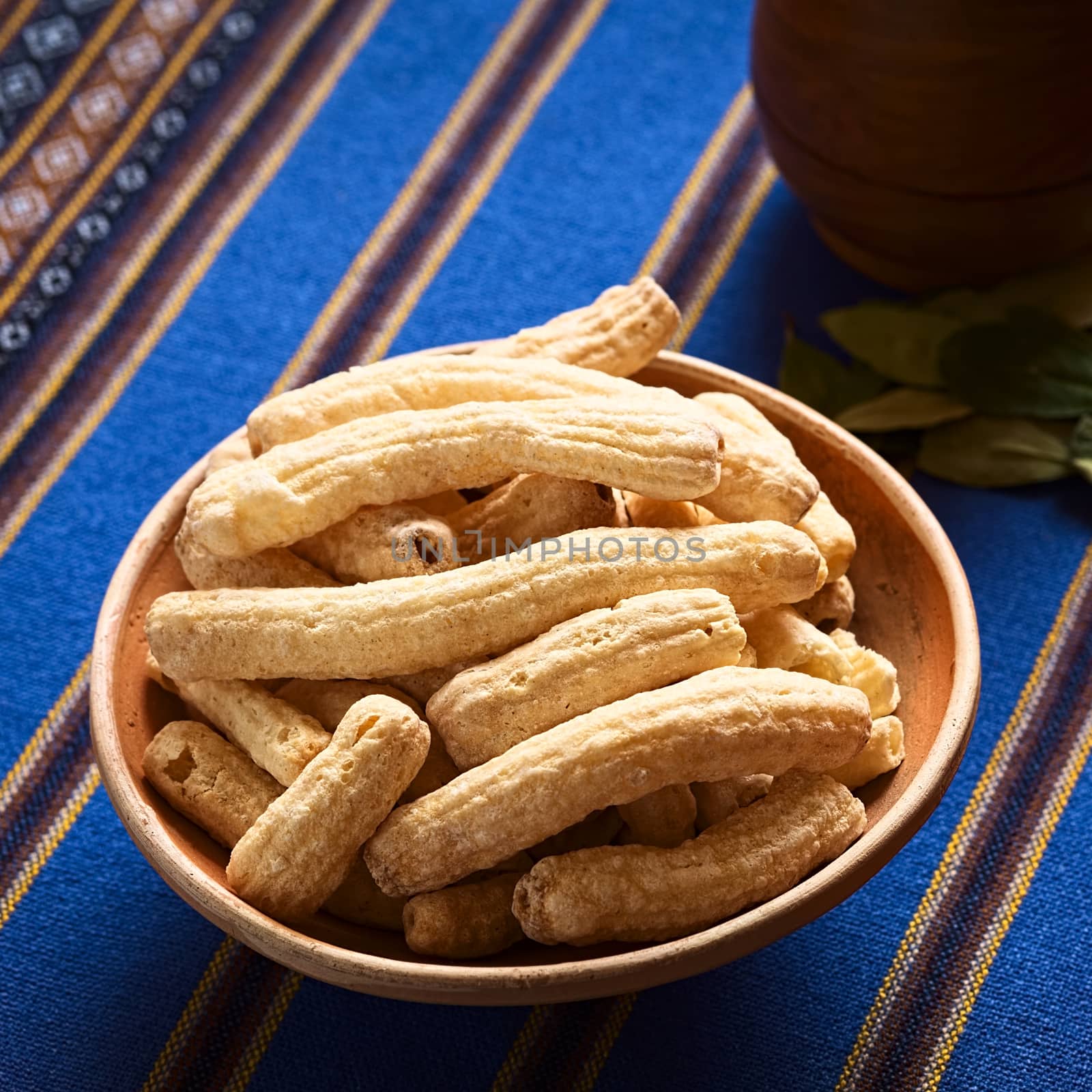 Sweetened popped pasta eaten as snack in Bolivia served in clay bowl with coca tea in the back, photographed with natural light (Selective Focus, Focus in the middle of the snack) 