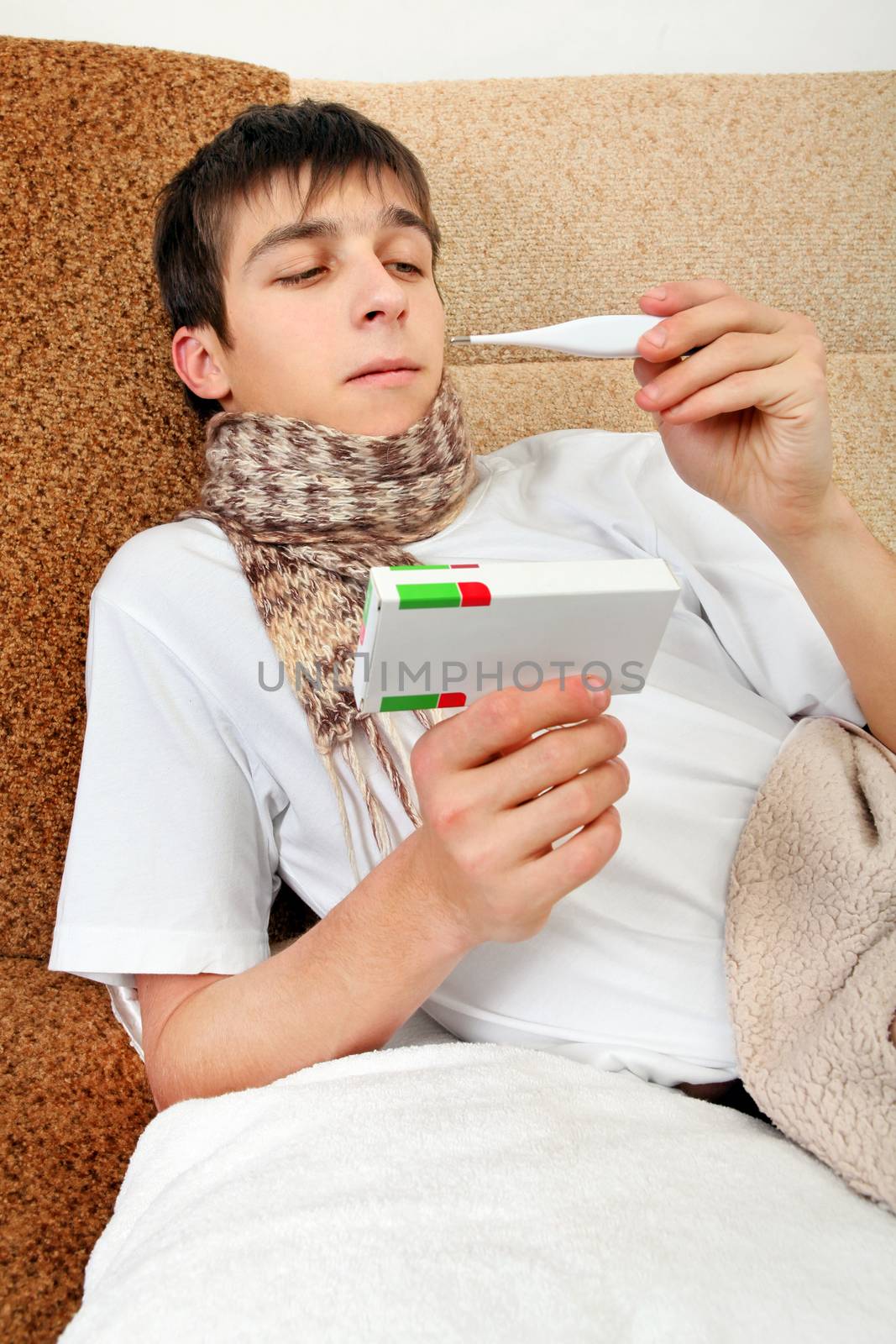 Sick Teenager with Thermometer and Drug on the Sofa at the Home