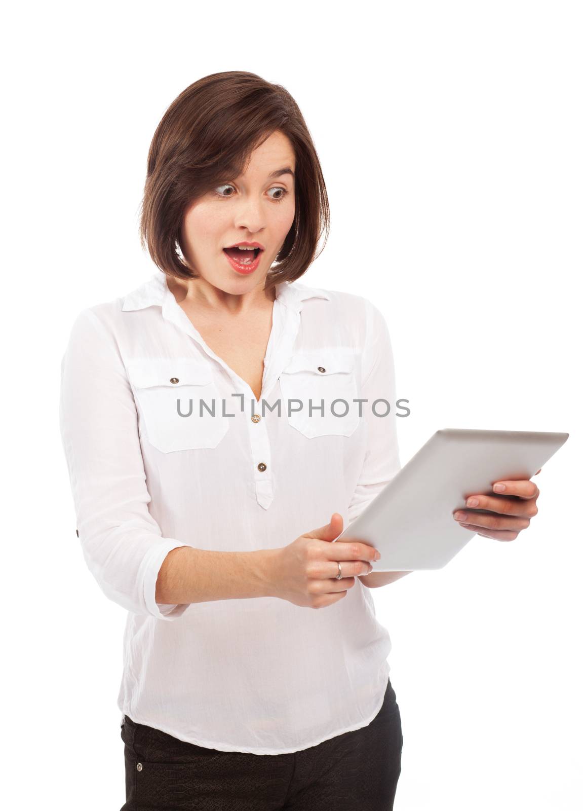 Young brunette reading something on an electronic tablet and looking very surprised, isolated on white