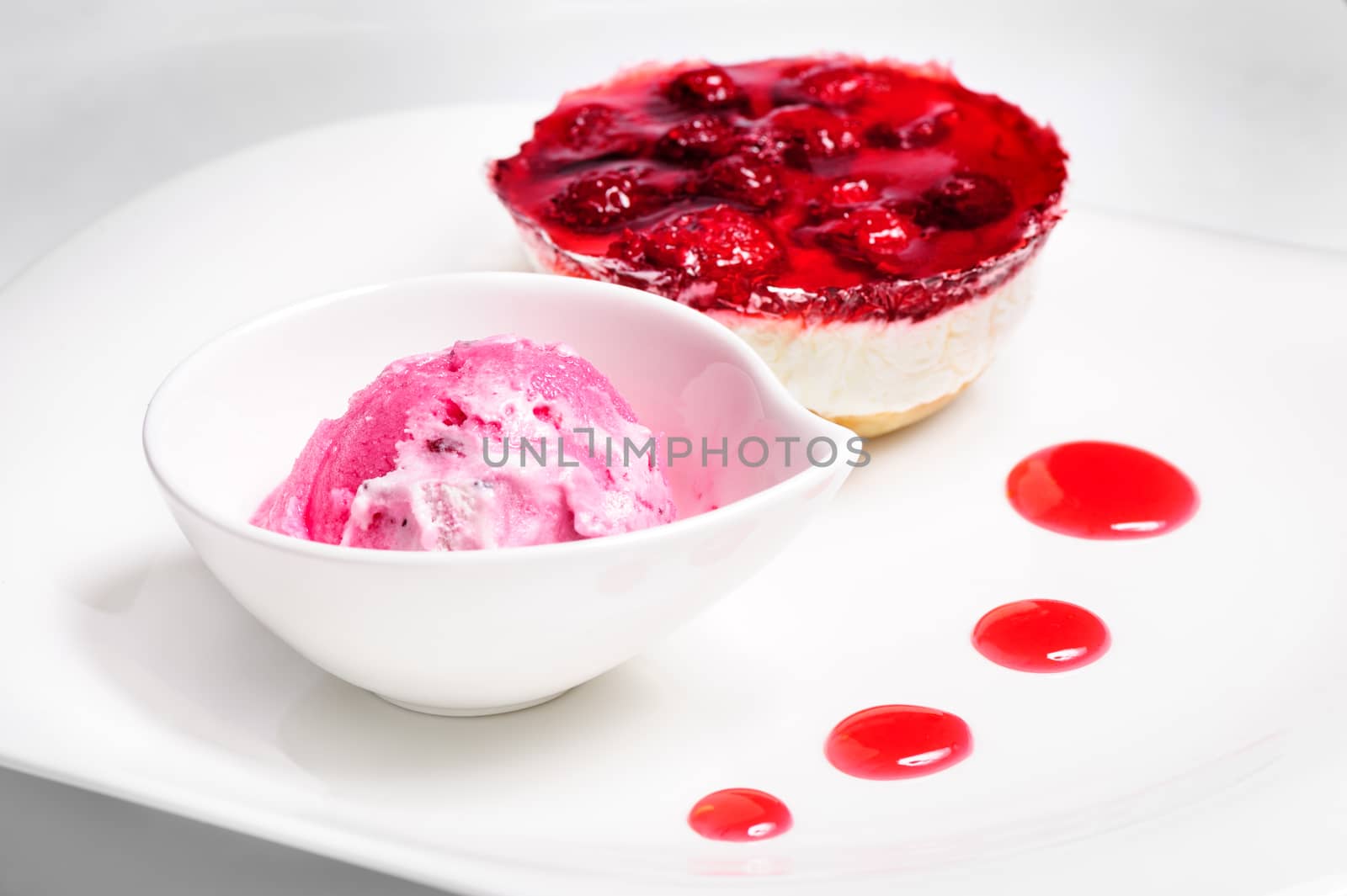 Raspberry layered cheese cake and pink ice cream ball on white  plate, not isolated