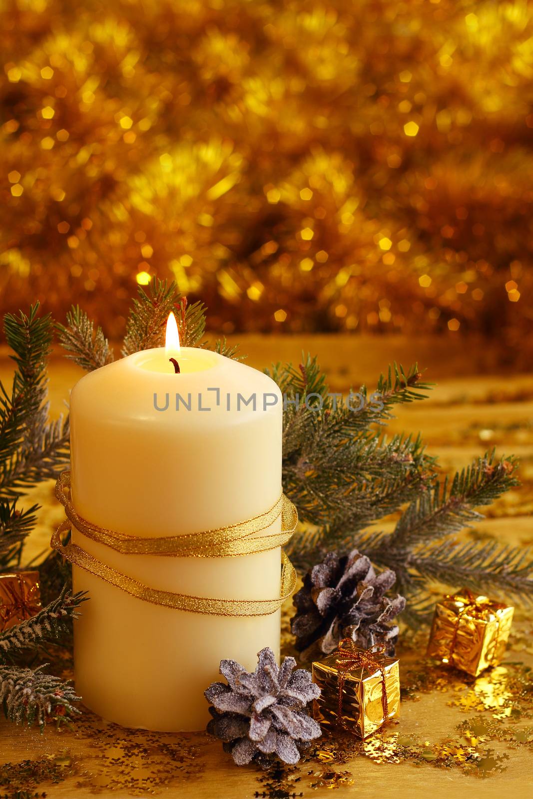 Christmas decorative burning candle, fir branch and decor over golden bokeh background