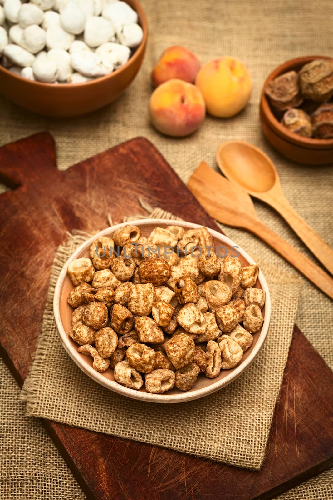 Caramelized roasted pasta, a popular Bolivian snack, served in small bowl with peach in the back, photographed  with natural light (Selective Focus, Focus on the top of the snack in the bowl)
