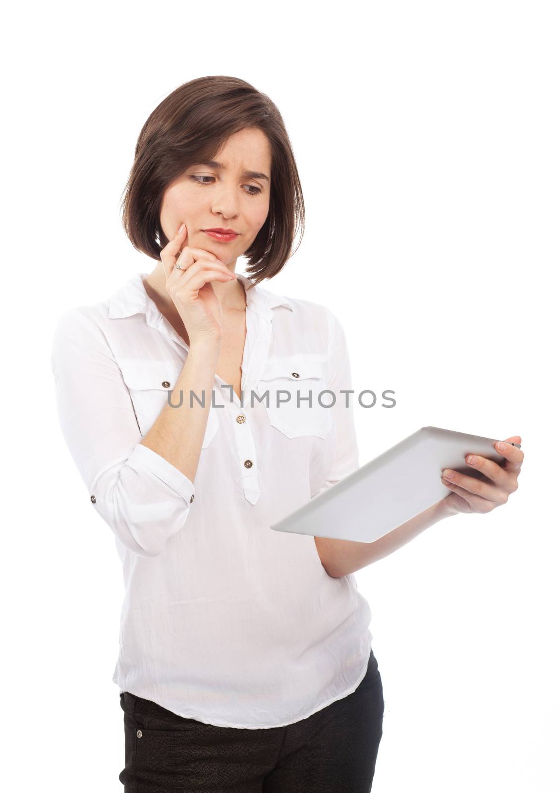 Young brunette holding and reading something on a touchpad with a wondering face, isolated on white
