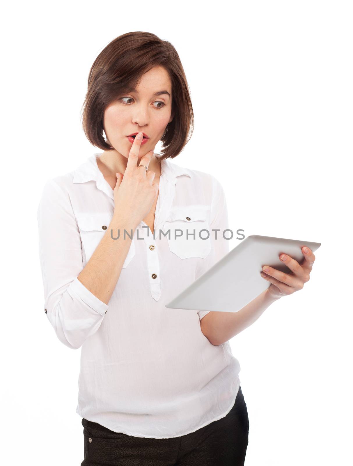 Young brunette watching something on an electronic tablet and looking positively surprised, isolated on white