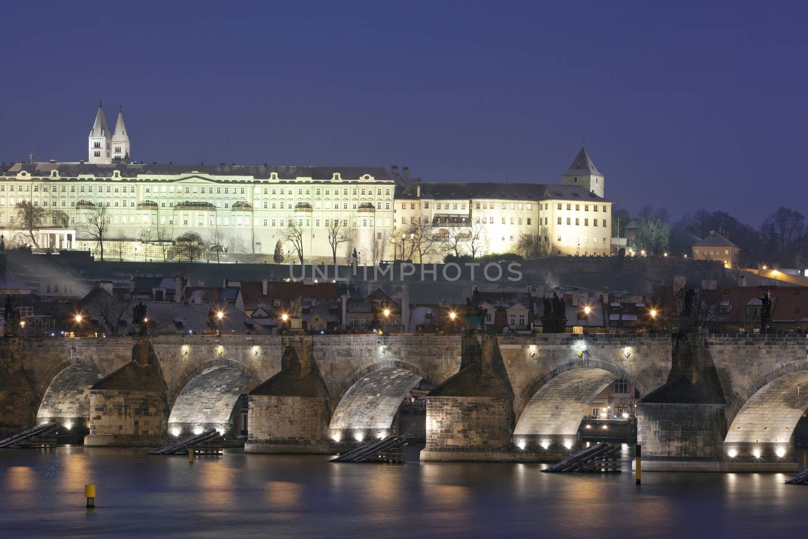 prague in winter - charles bridge and hradcany castle at dusk