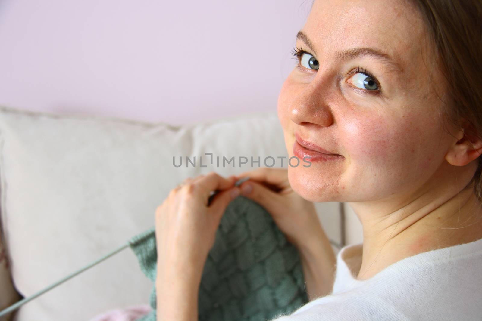 happy young woman knitting on sofa