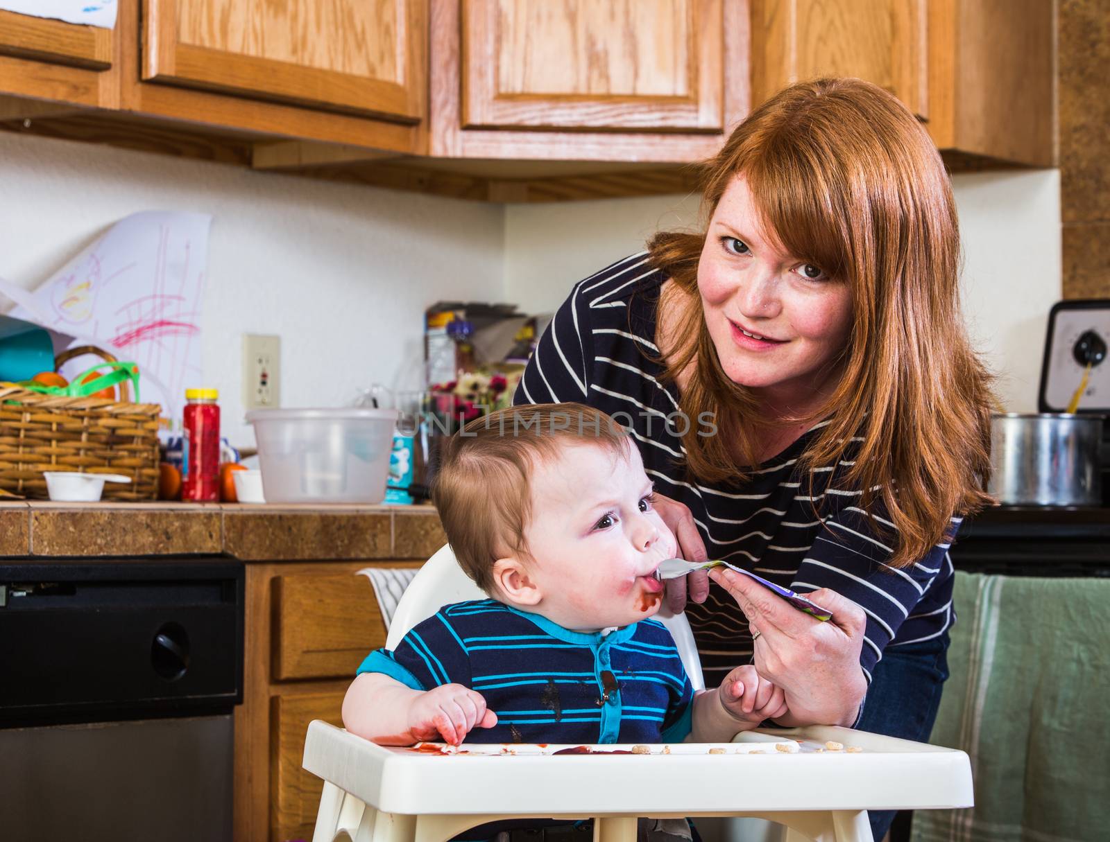 A woman feeds her baby juice in the kitchen