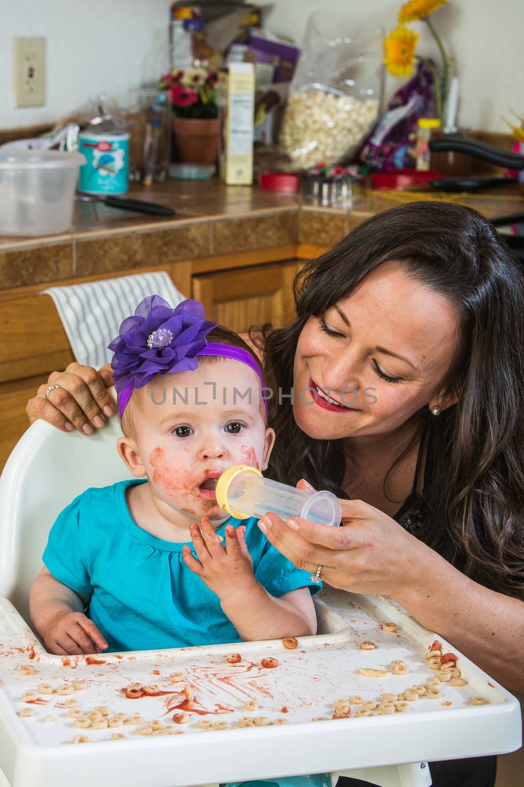 A woman in the kitchen feeds her baby from bottle