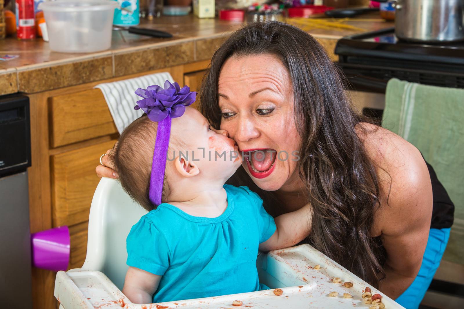 Baby girl gives her mother a kiss on cheek in the kitchen