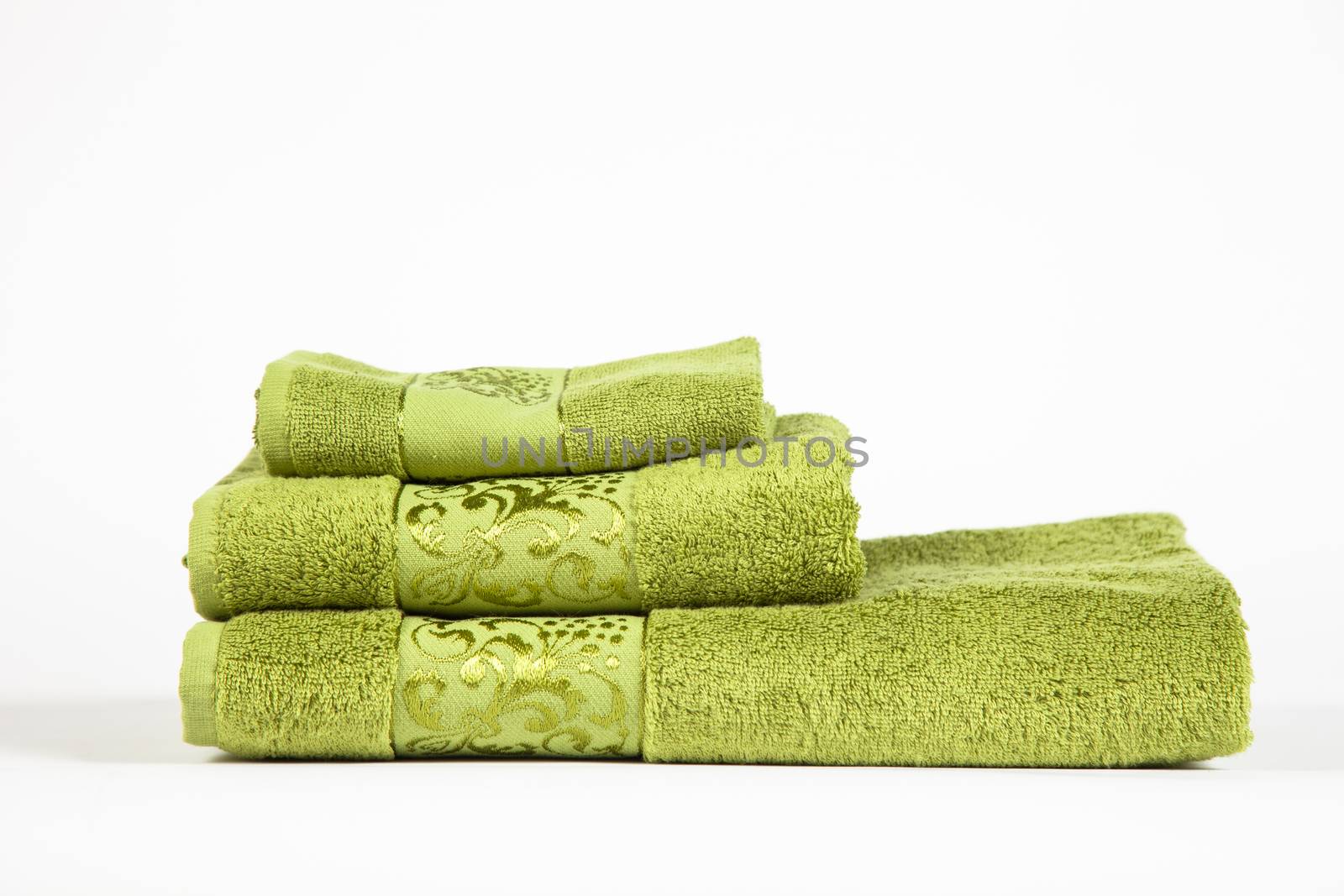 stack of green bathroom towels on white background