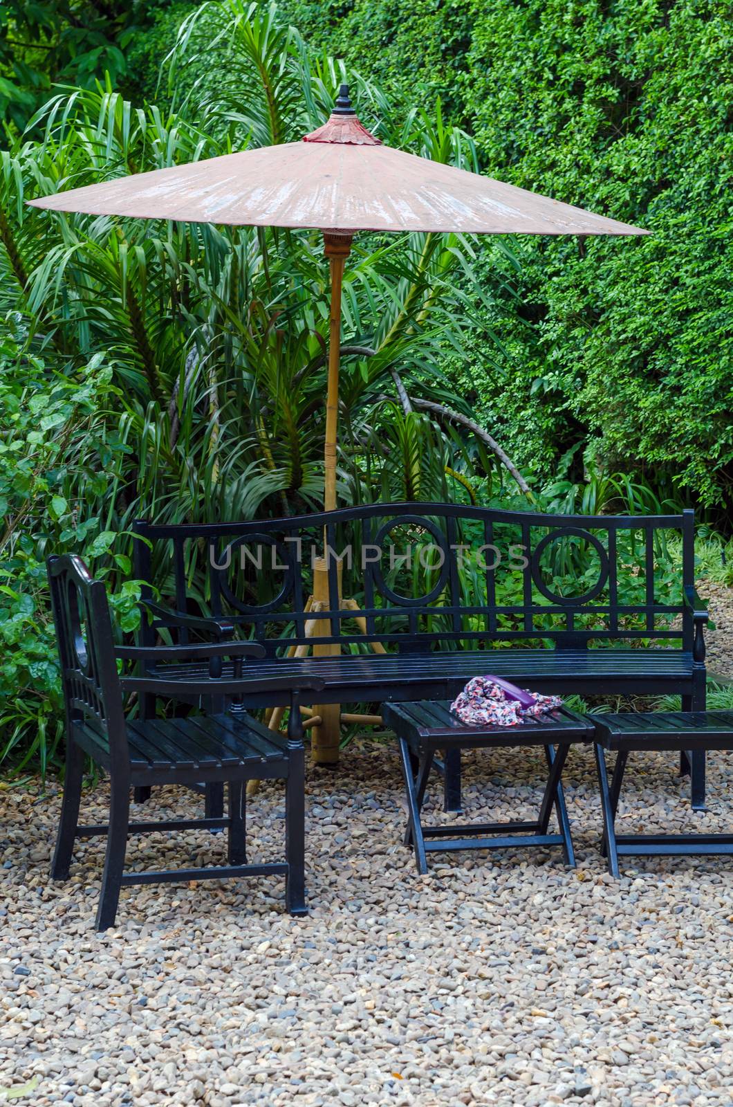 Wooden Bench and table in a pebble garden with umbrella