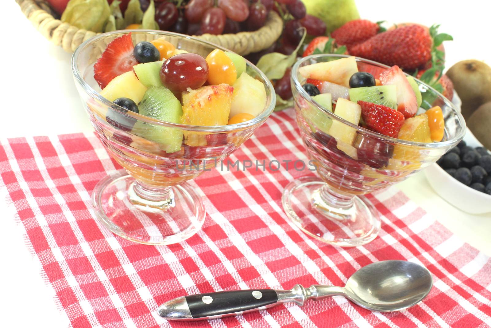 Fruit salad in a bowl on checkered napkin on a light background