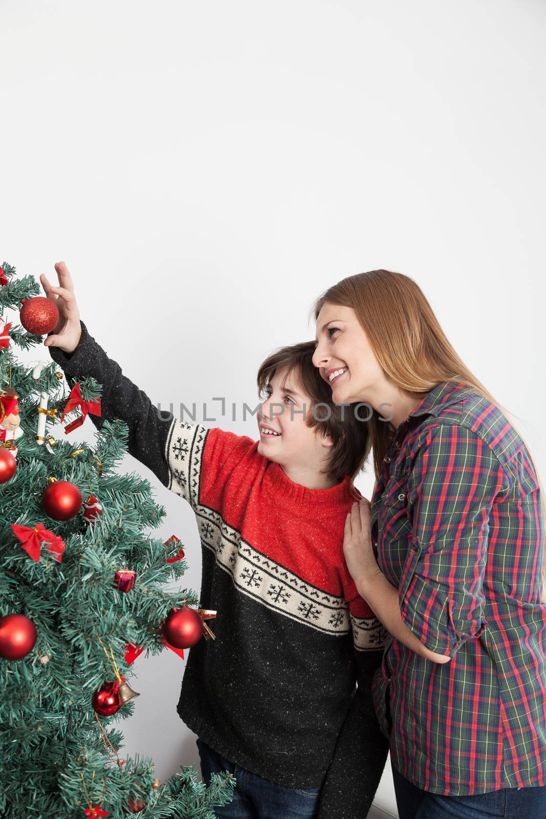Mom with her son putting ornaments on the christmas tree by ifilms