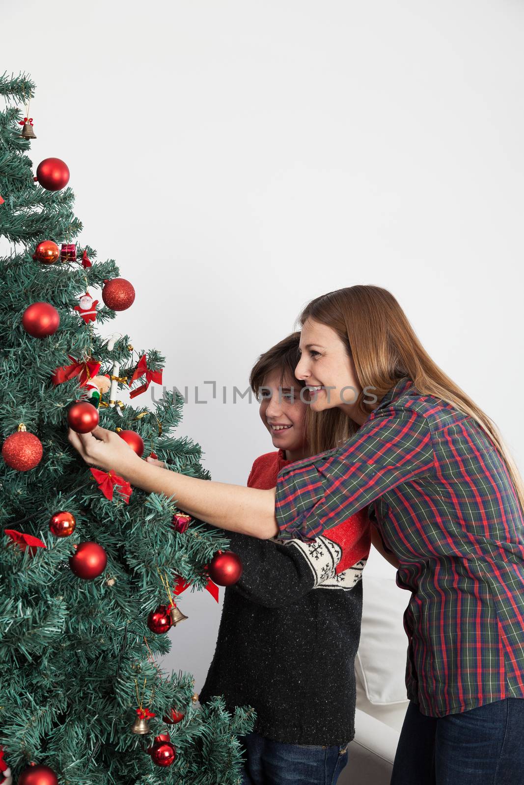 Mom with her son decorating the christmas tree by ifilms