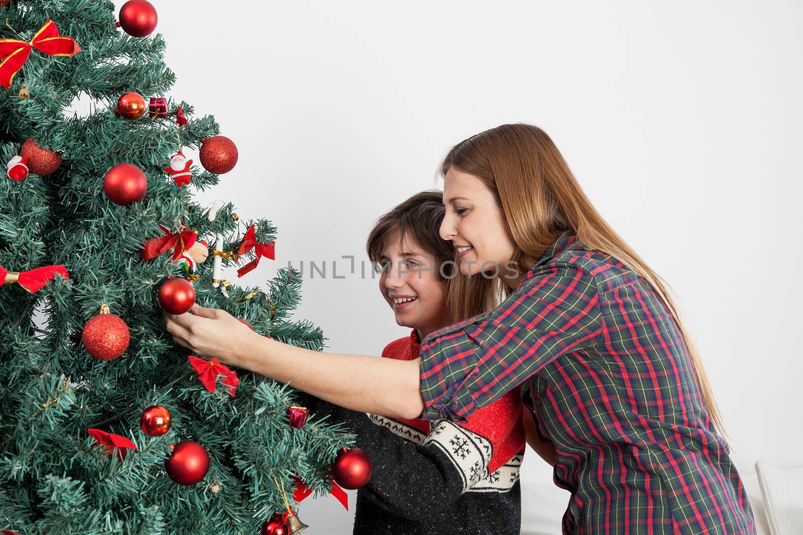 Happy mom and son decortating the christmas tree by ifilms