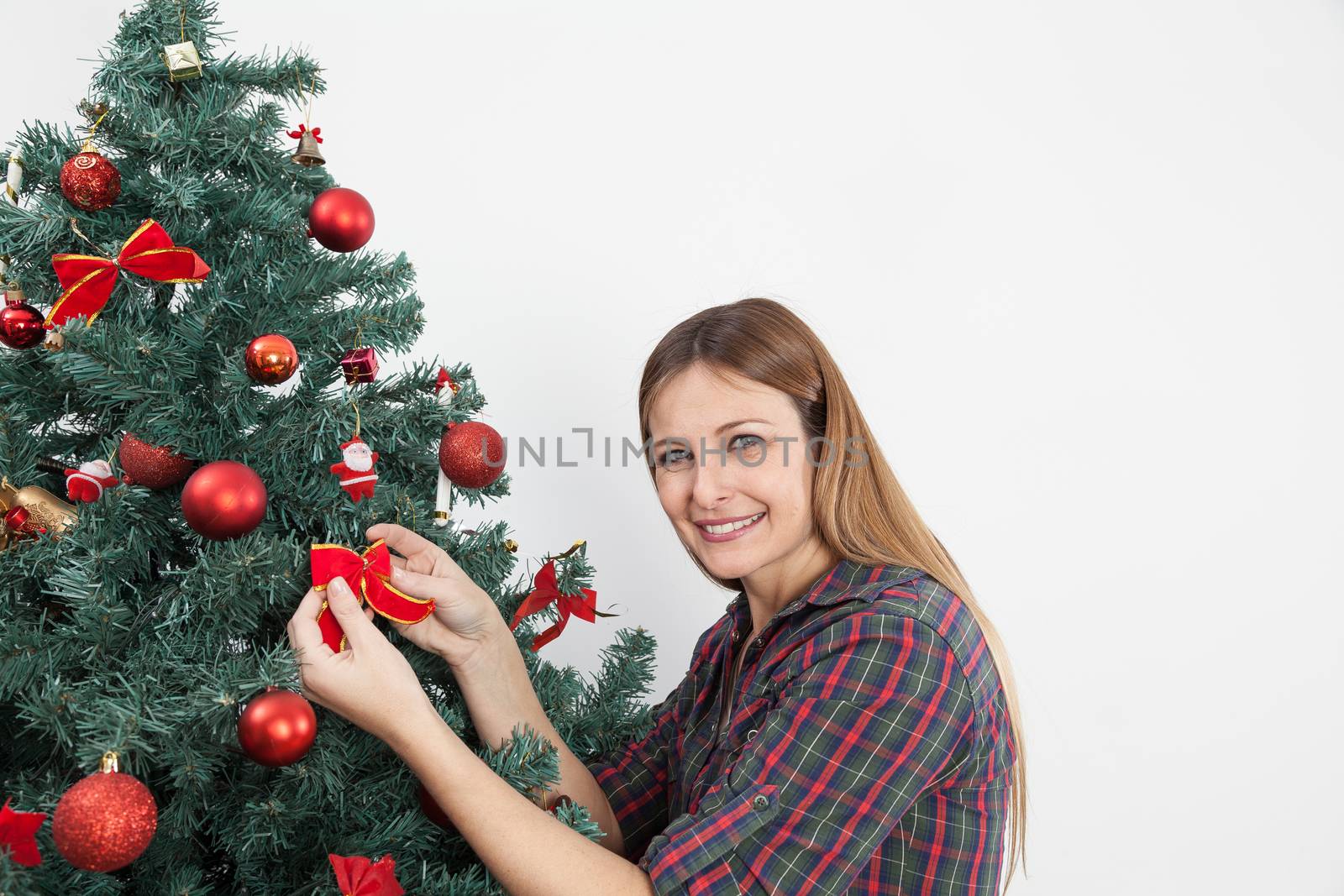Woman putting a bow in the christmas tree by ifilms