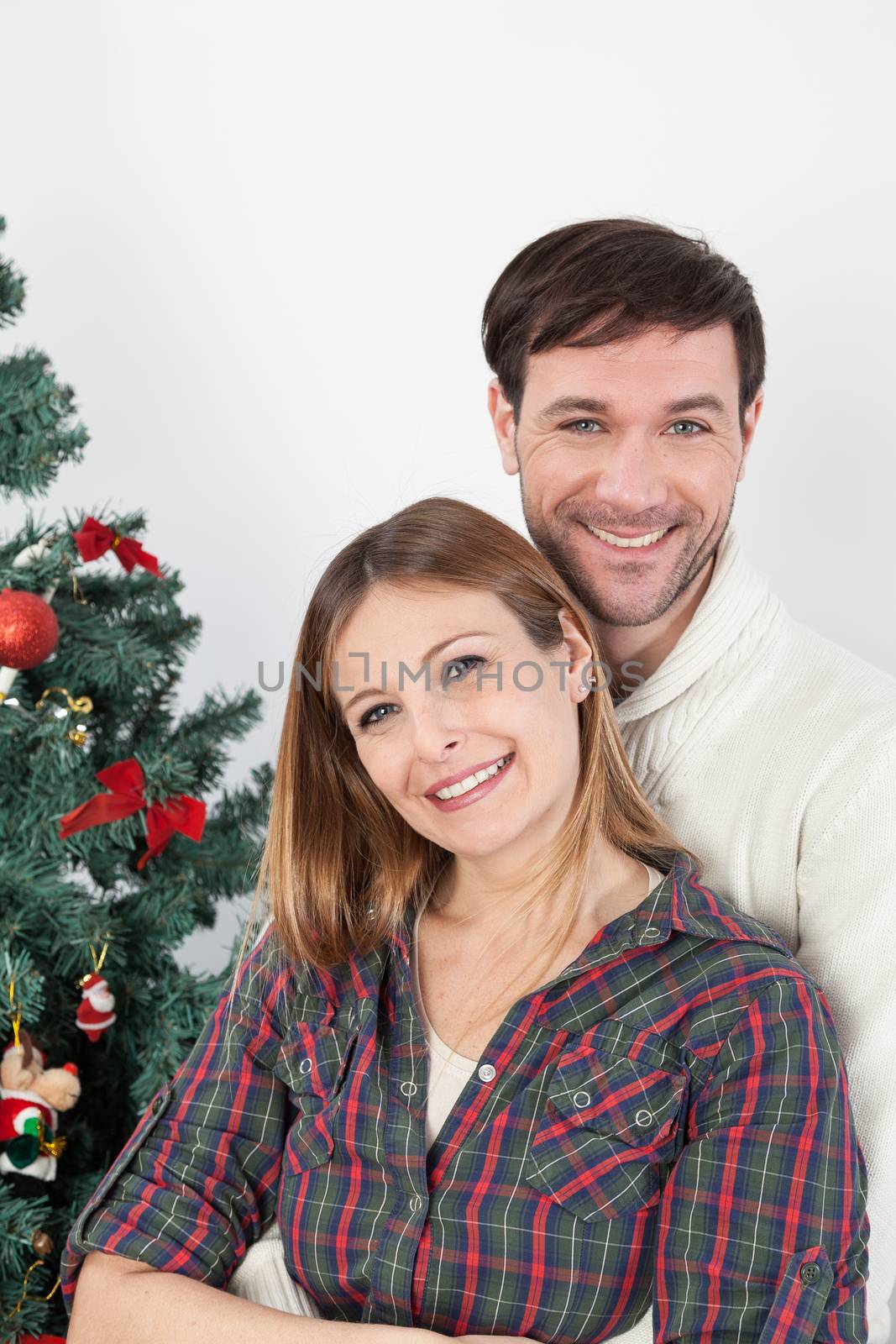 Couple hugging himself beside the christmas tree by ifilms